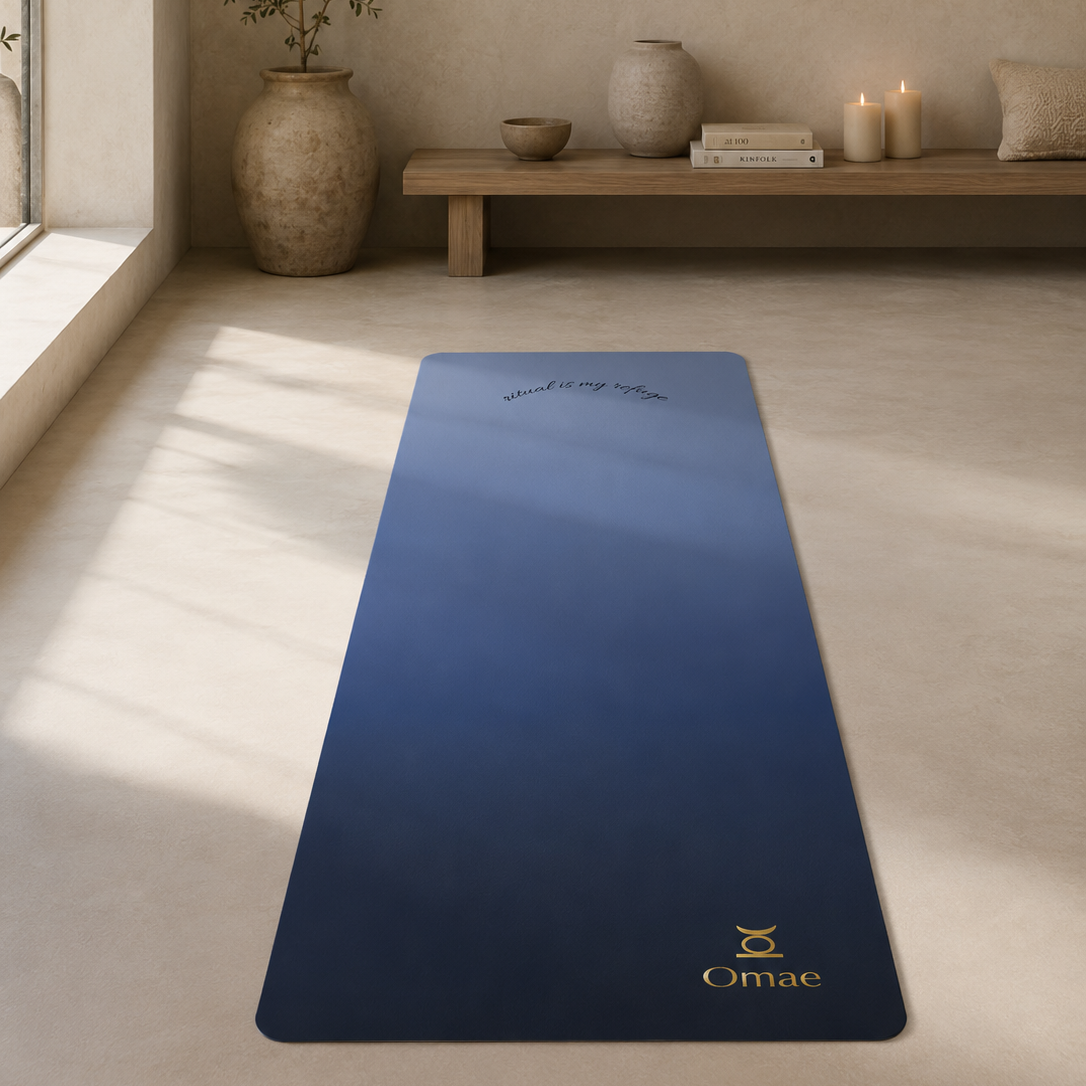 Blue yoga mat with 'Omae' branding on a light wooden floor in a serene room.
